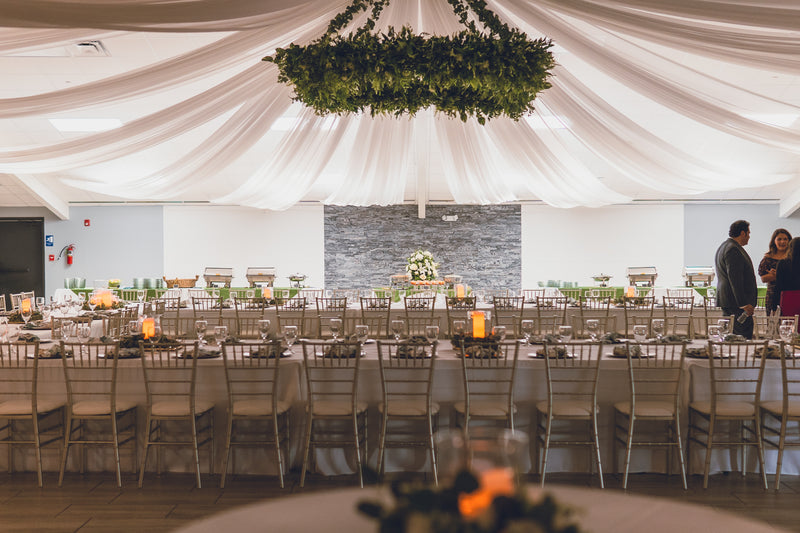 Wedding reception room with draped ceiling and long tables